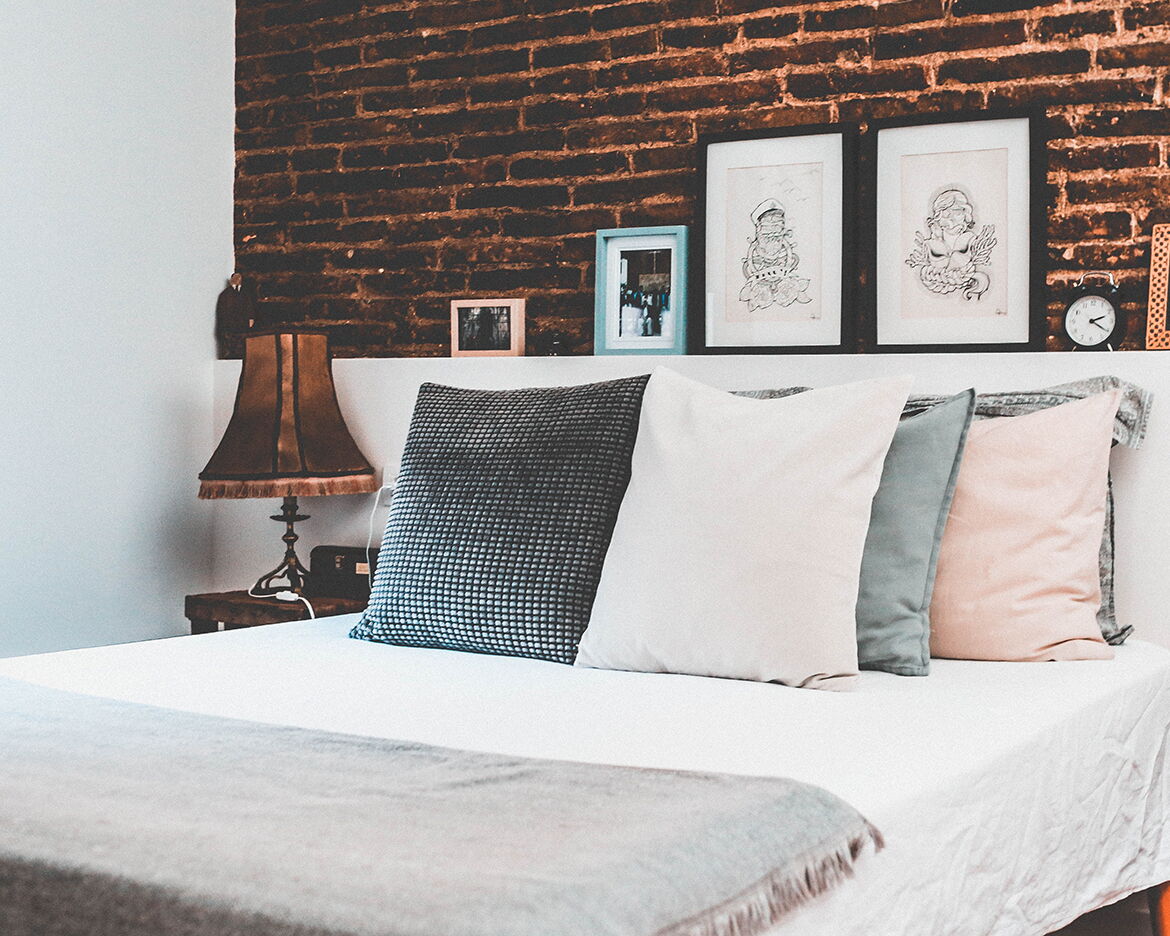 Frisch bezogenes Wasserbett mit weißer Wäsche vor einer Ziegelwand