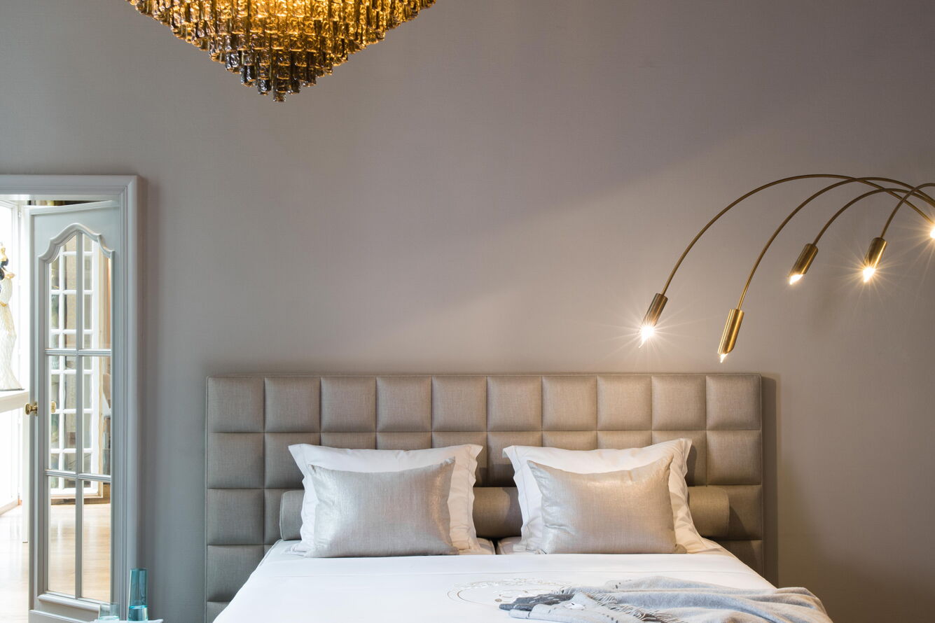 Boxspringbett mit geknöpftem Kopfteil unter einem Kronleuchter