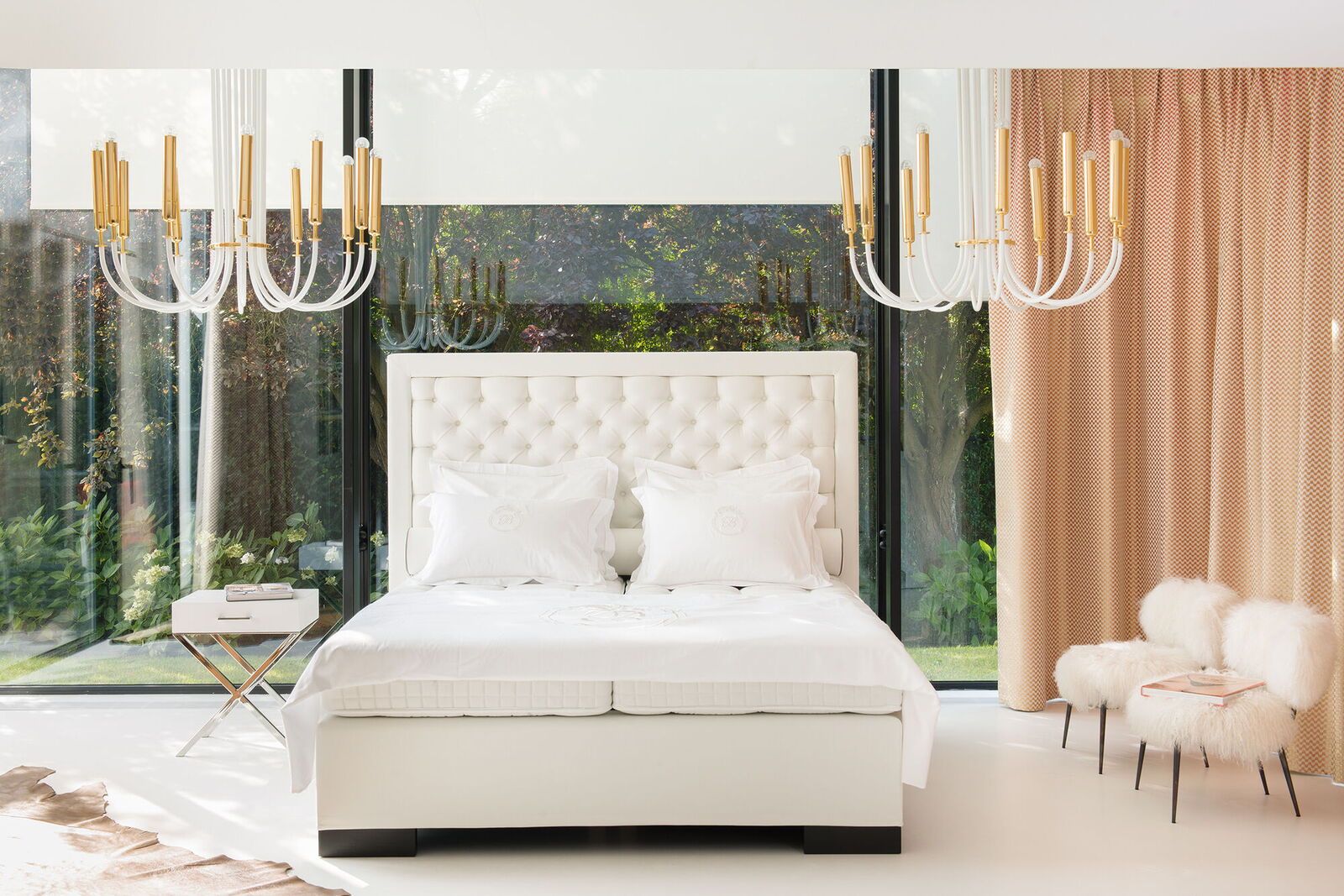 Weißes Boxspringbett mit hohem Kopfteil und Kronleuchter